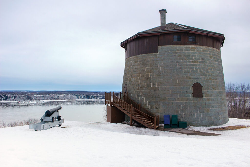 Photo of a early spring view of Martello Tower number 1, one of the three remaining 19th century British Martello towers that form part of the Fortifications of Québec National Historic Site of Canada on the Plains of Abraham, National Battlefields Park, Québec City, Québec. The St. Lawrence River can be seen in the background.